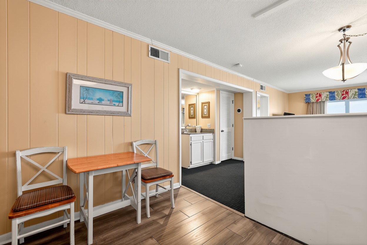 A hotel lobby with a small table and chairs, a counter, and artwork on the wall.